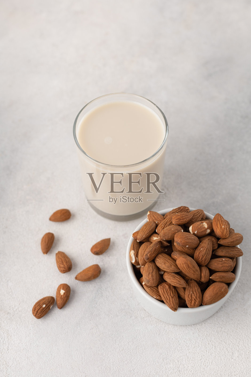 一杯杏仁奶和一碗坚果，背景光线较亮照片摄影图片