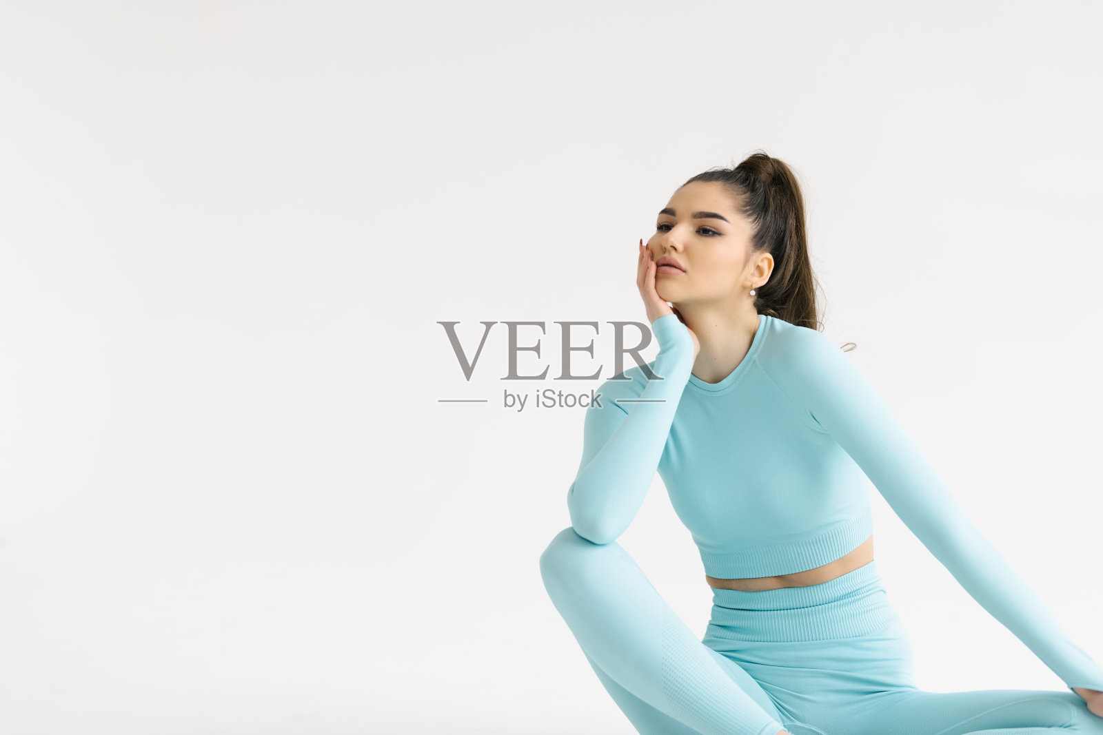 健身的女人在锻炼后微笑。健康和健康的女运动员休息，坐在地板上的运动服在白色的背景。照片摄影图片