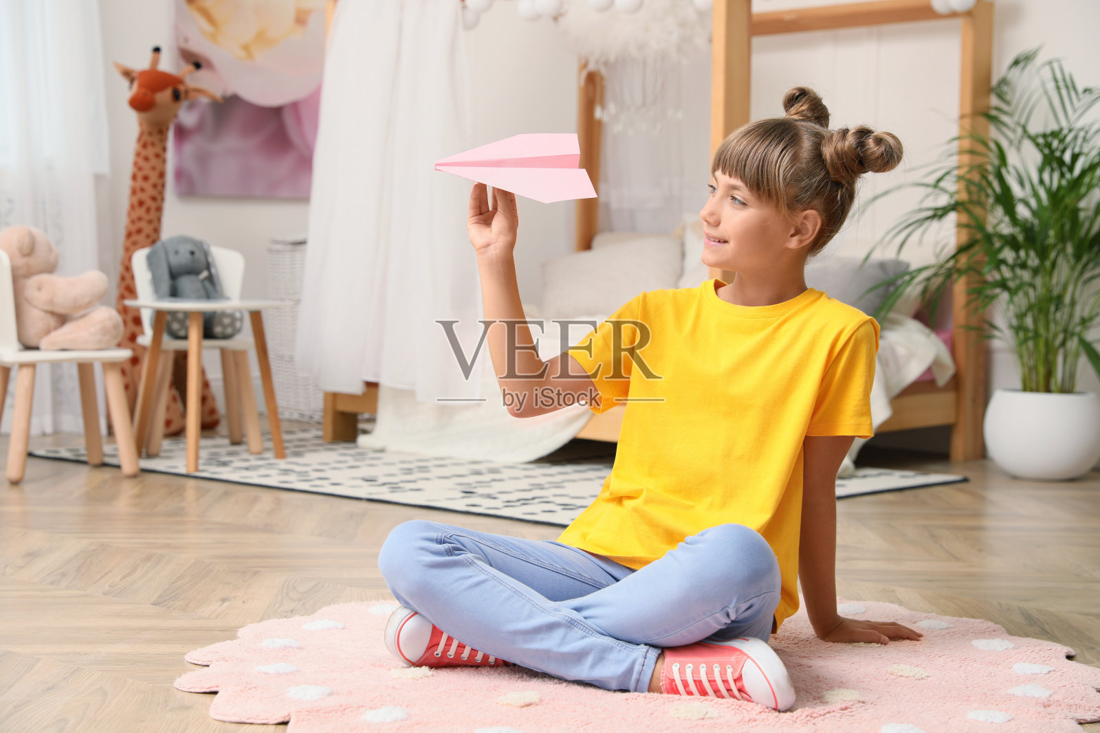 可爱的小女孩在房间的地板上玩纸飞机。空间的文本照片摄影图片