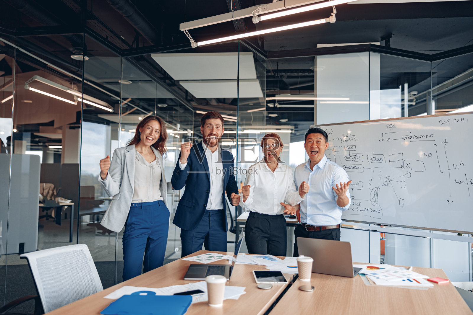 穿着正装、面带微笑的商务人士愉快地站在现代化的办公室里照片摄影图片