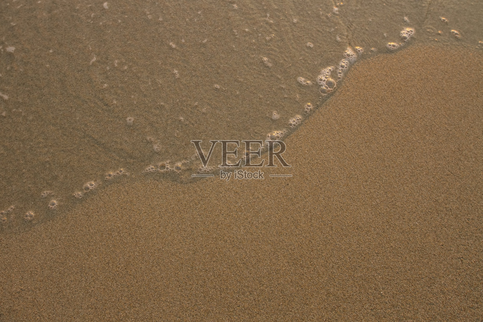 柔和的海浪拍打着沙滩的纹理。照片摄影图片