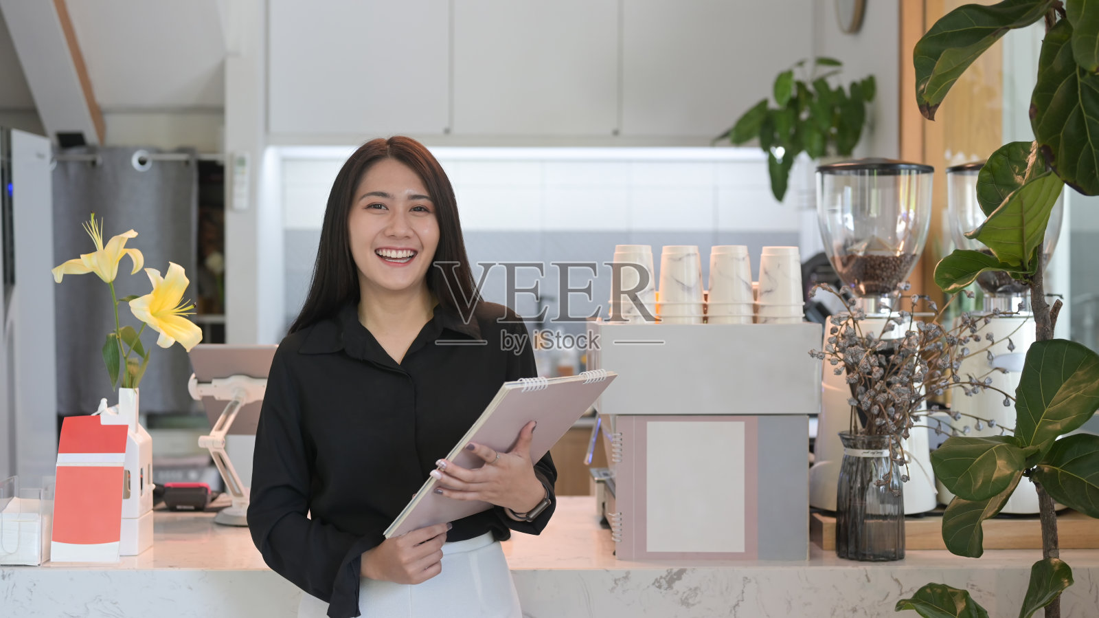 成功的女企业主站在咖啡店柜台后面，对着镜头微笑。照片摄影图片