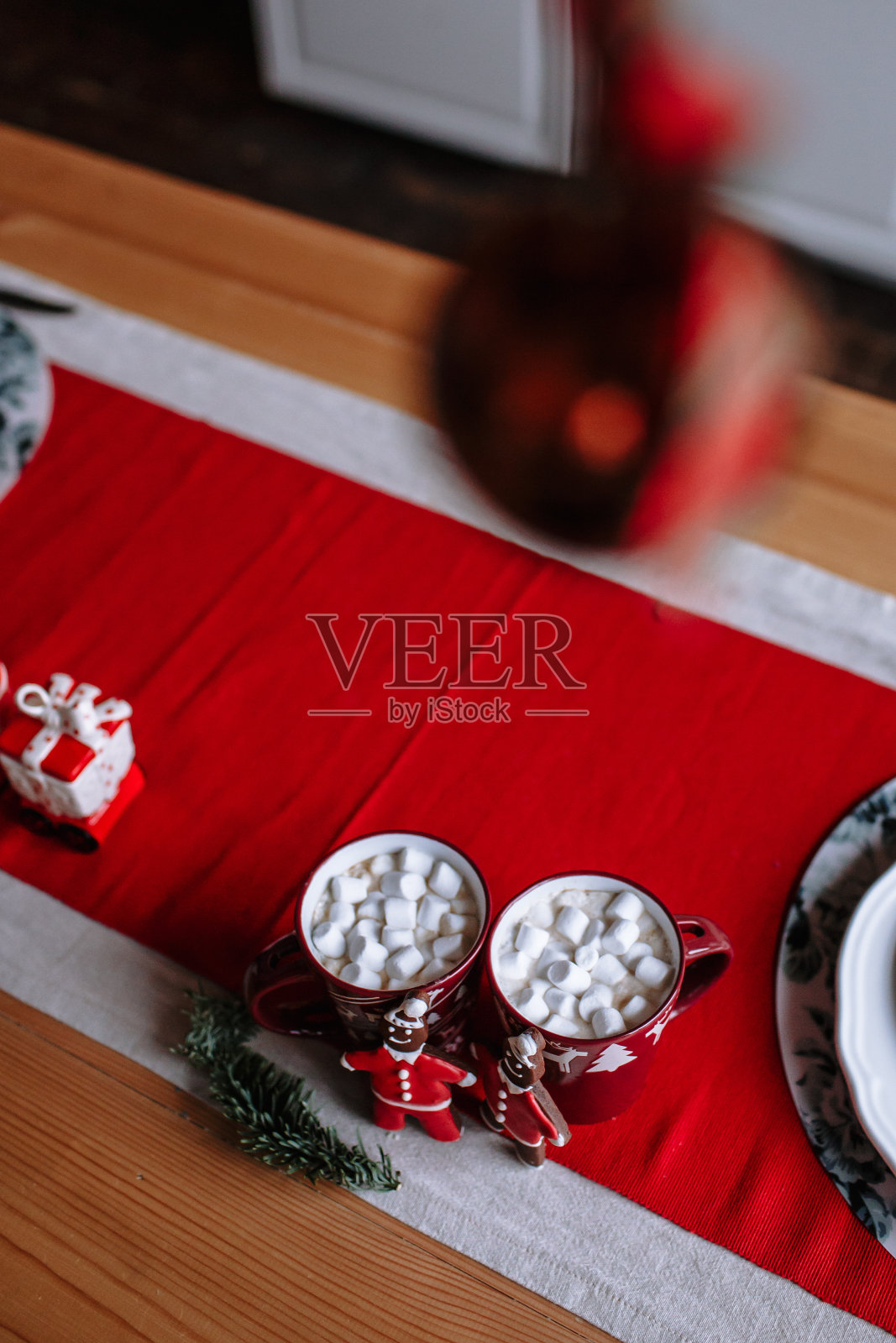 桌子上放着漂亮的杯子，还有火车形状的厨房用具。厨房为迎接圣诞节而装饰。杯子旁边是一个穿着圣诞老人服装的男人形状的姜饼。照片摄影图片