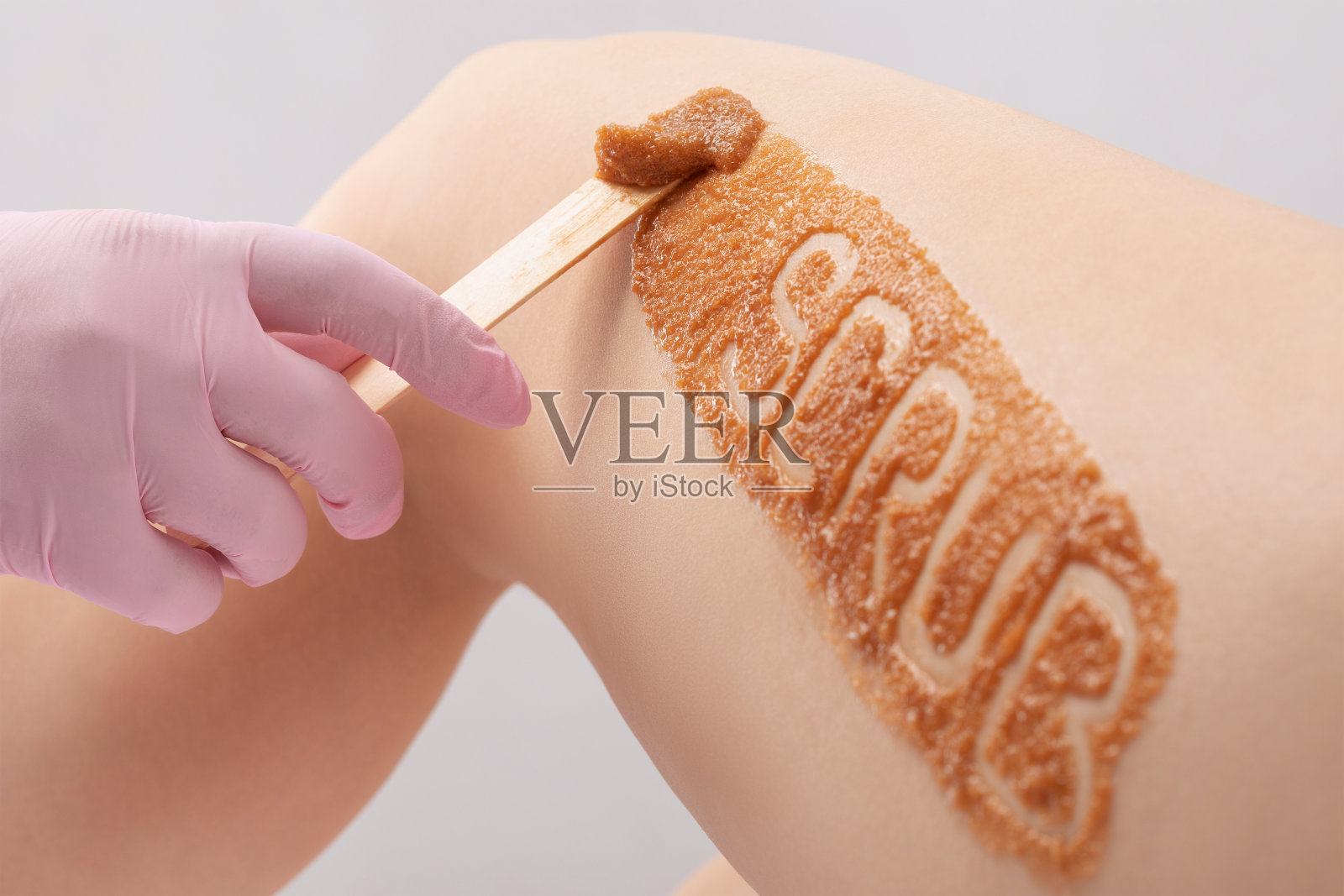 美容师在一个女人的大腿上做美容脱皮手术。美容院的水疗程序。照片摄影图片