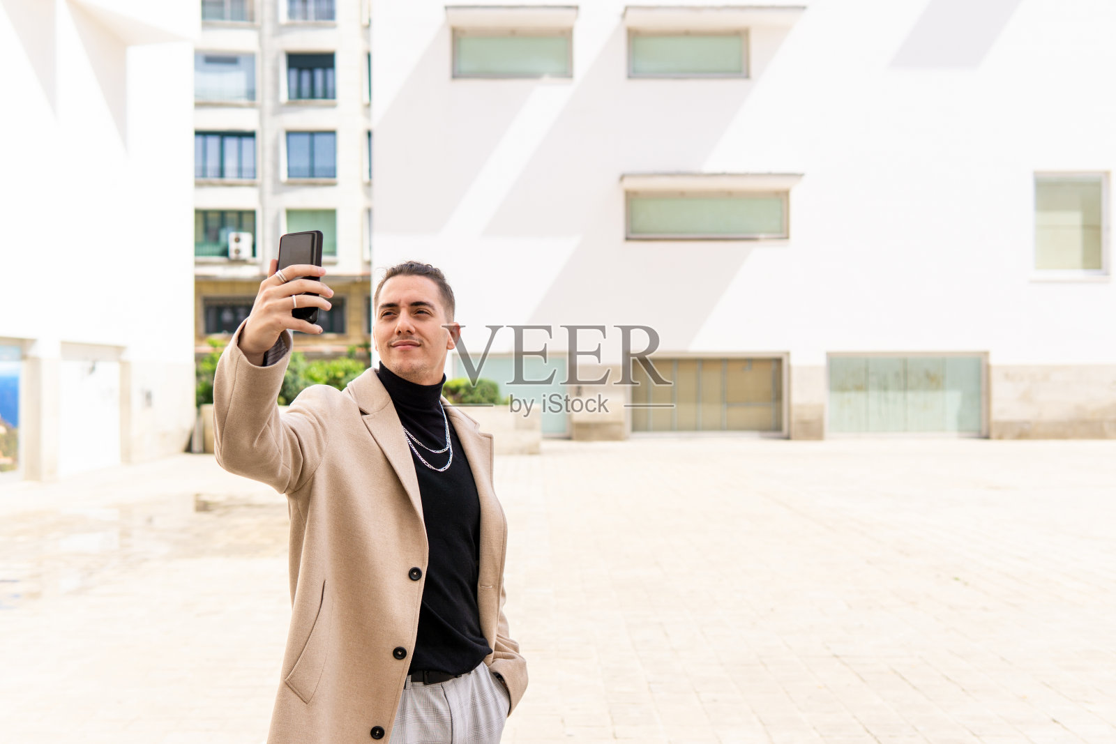 一名年轻的混血男子在城市里用智能手机自拍。社交媒体，沟通，移动应用，商业，生活理念照片摄影图片