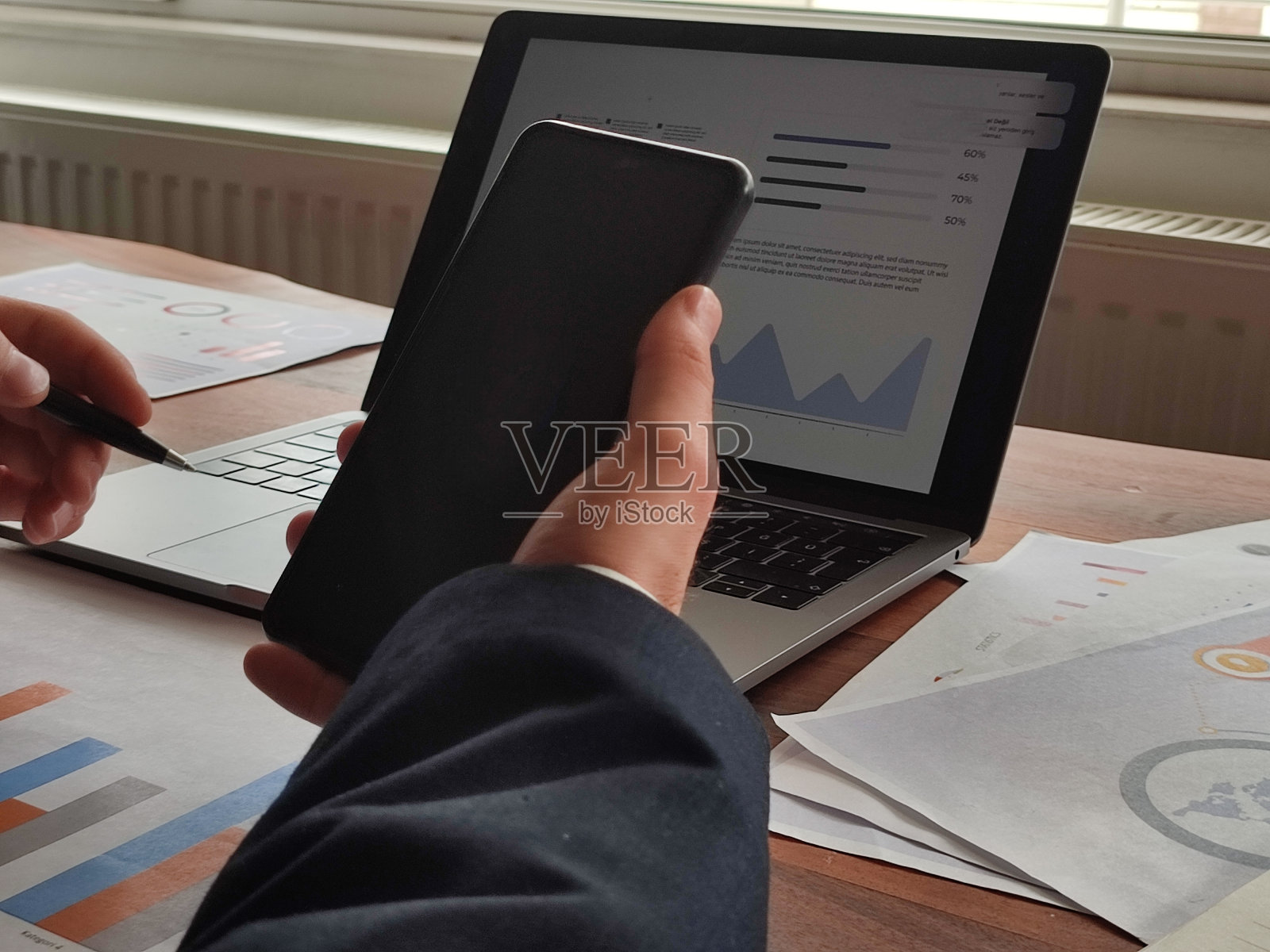 一个商人在他的办公桌前用智能手机发短信照片摄影图片