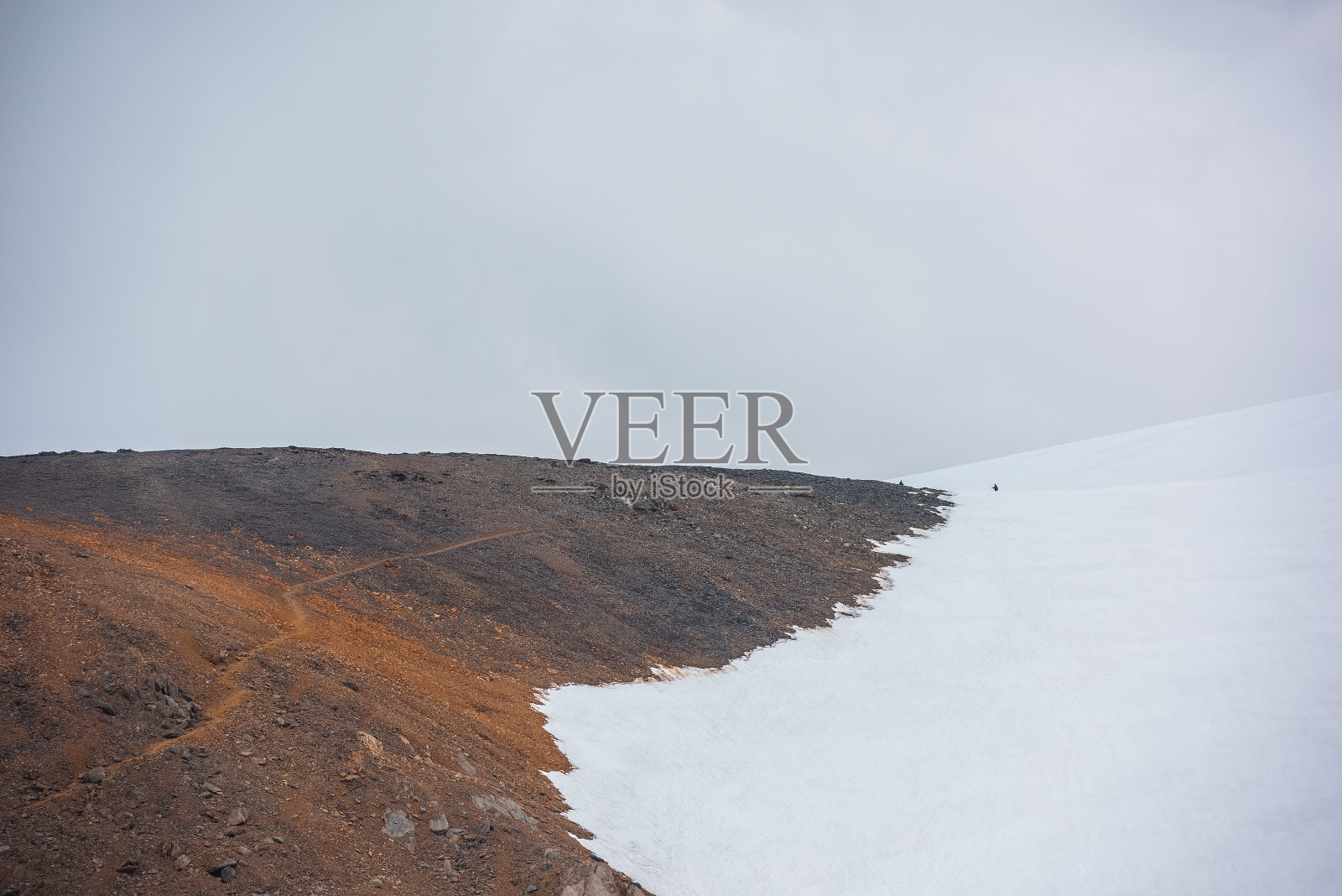 风景优美，石质山坡上的远足小径，在阳光下灰色多云的天空下，高雪山。在阳光明媚的岩石山坡上的旅游路线，在多变的天气下到大雪山。照片摄影图片