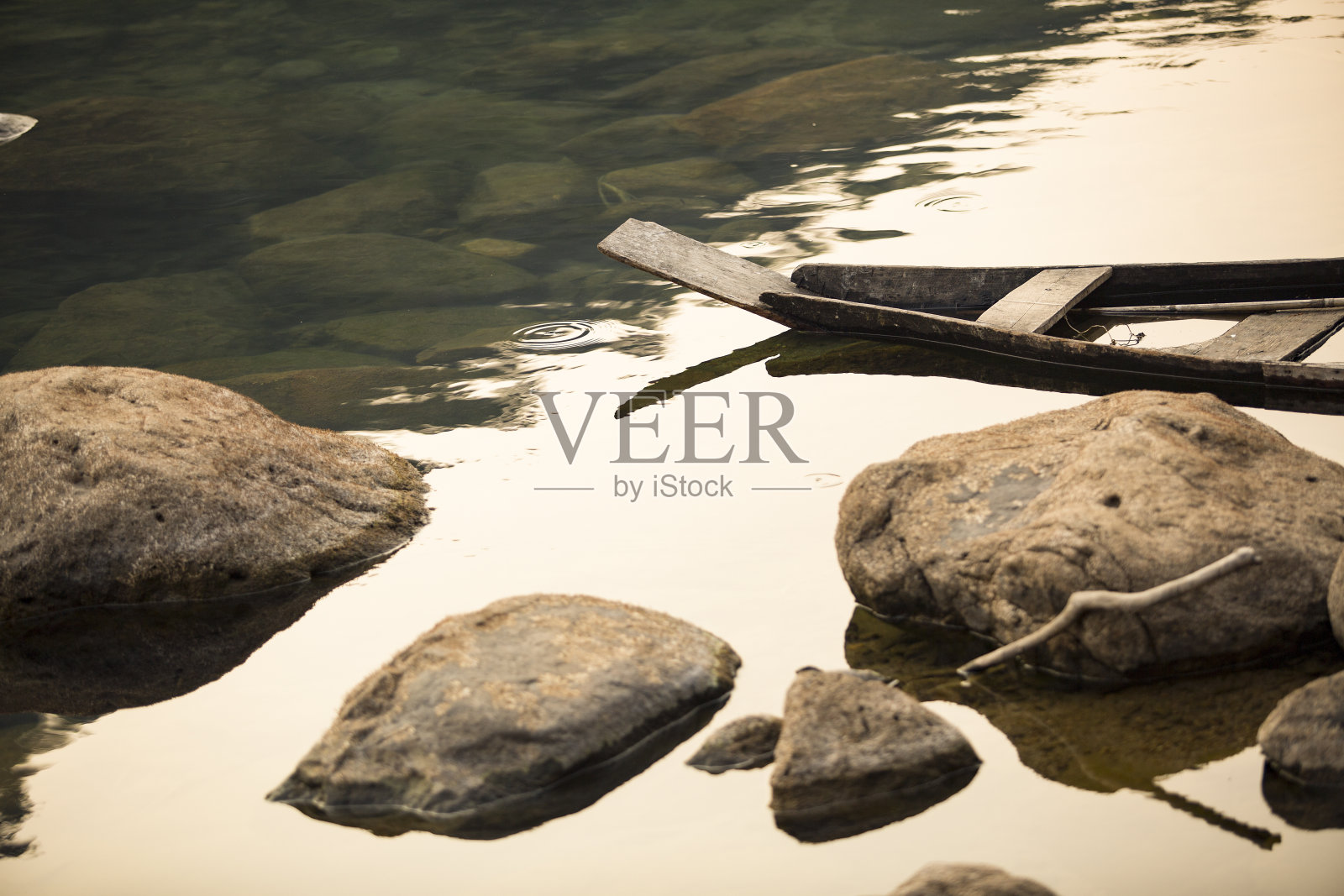 一艘旧木船躺在多岩石的湖边。照片摄影图片