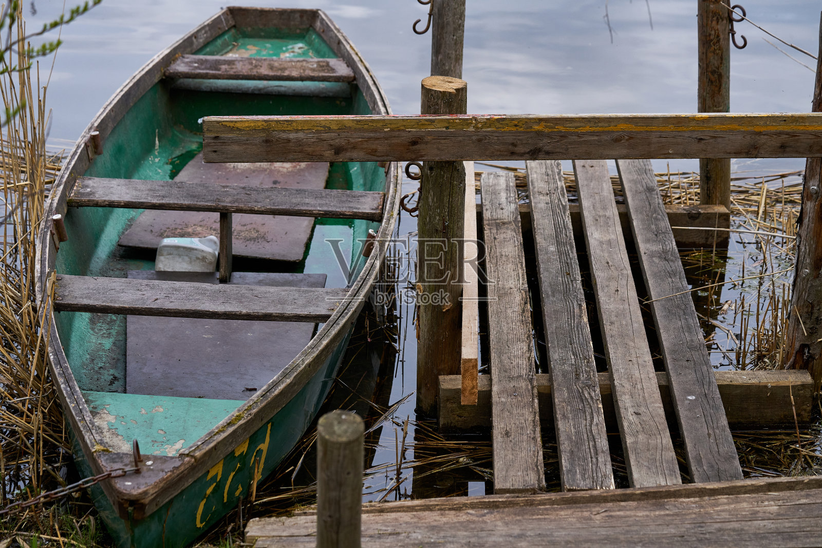 停靠码头附近湖面上漂浮着一艘绿色小船照片摄影图片