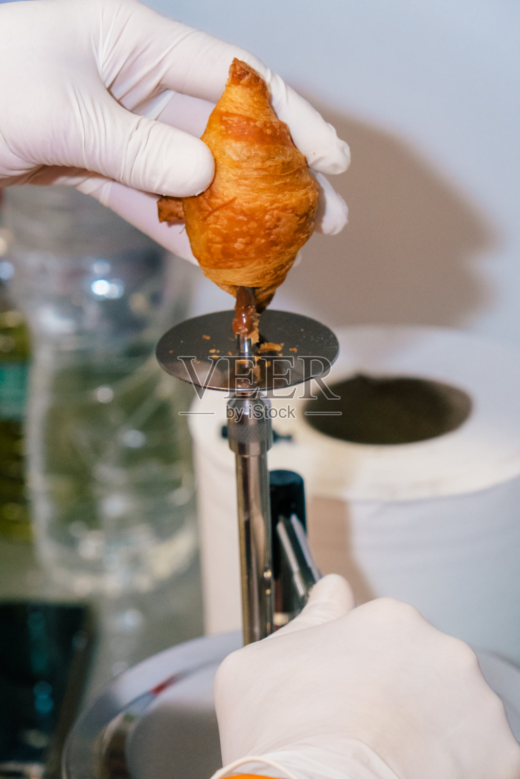 糖果师用机器给羊角面包填充巧克力。照片摄影图片