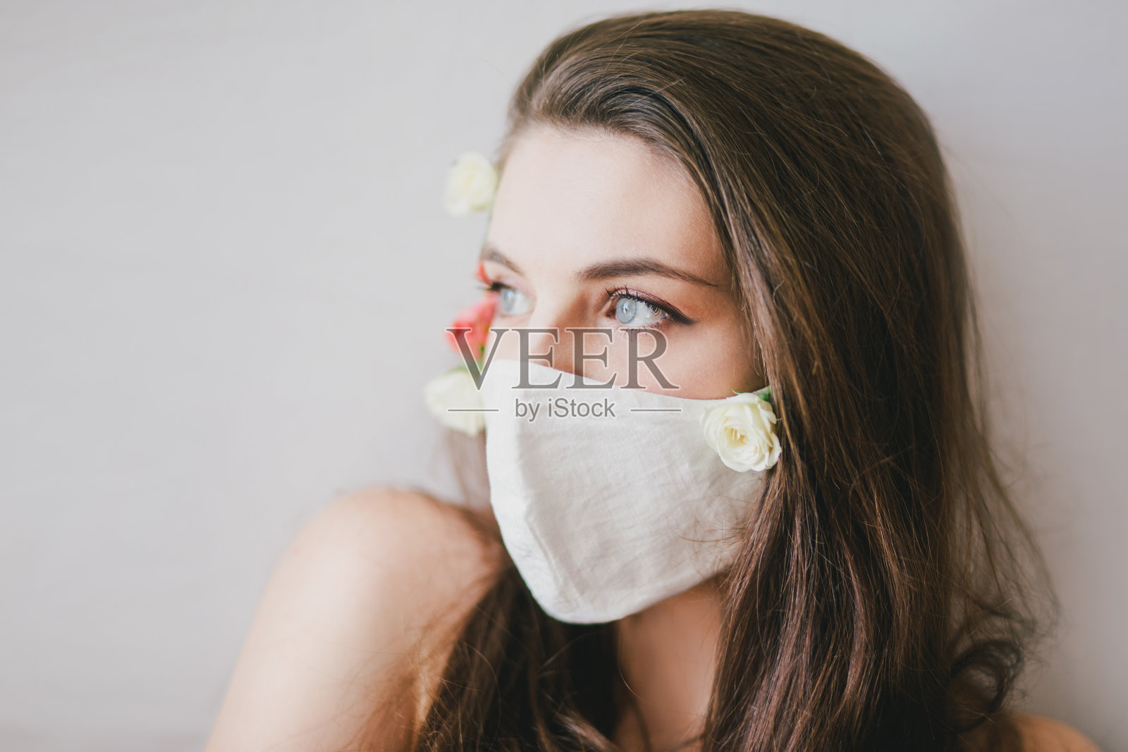 年轻女子戴着带着玫瑰花的防护面具。照片摄影图片