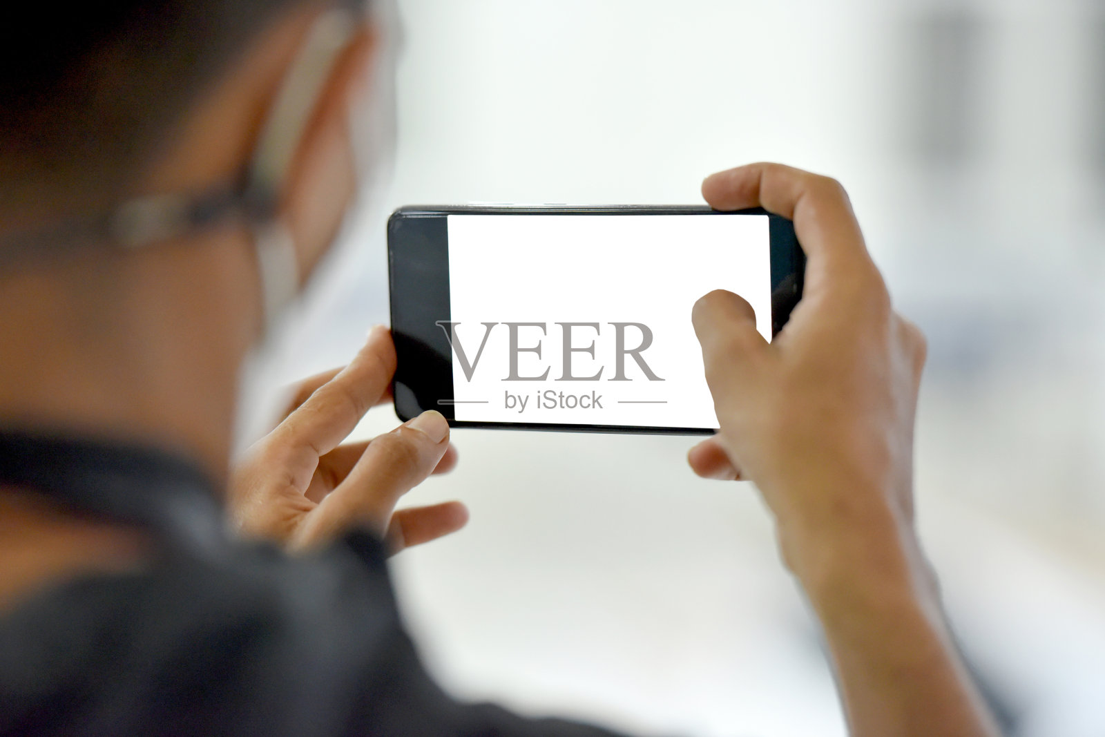 裁剪图像的男性艺术家站在手里拿着空白的白色屏幕智能手机在家里照片摄影图片