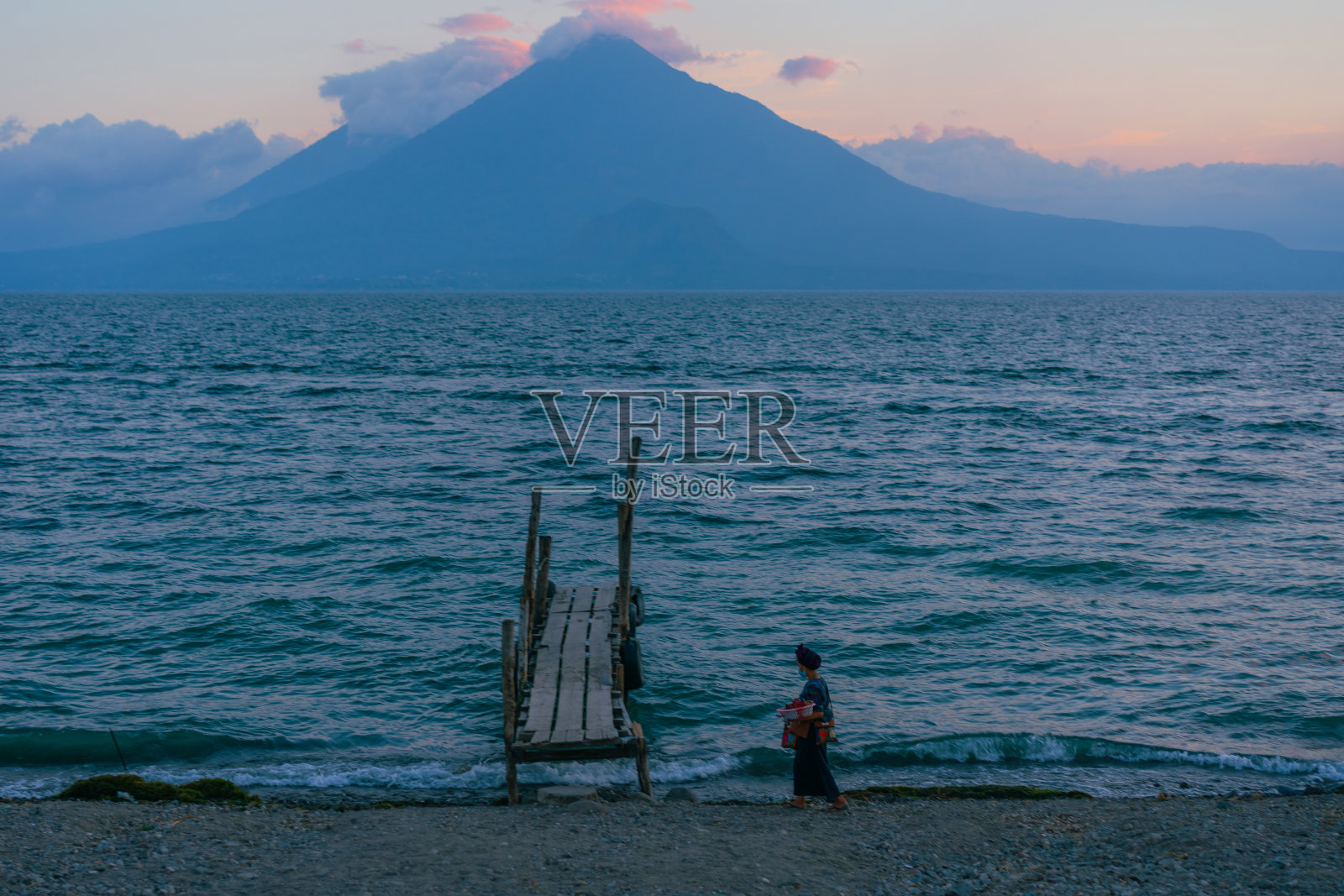 日落时分，危地马拉阿提特兰湖上卖东西的女人照片摄影图片