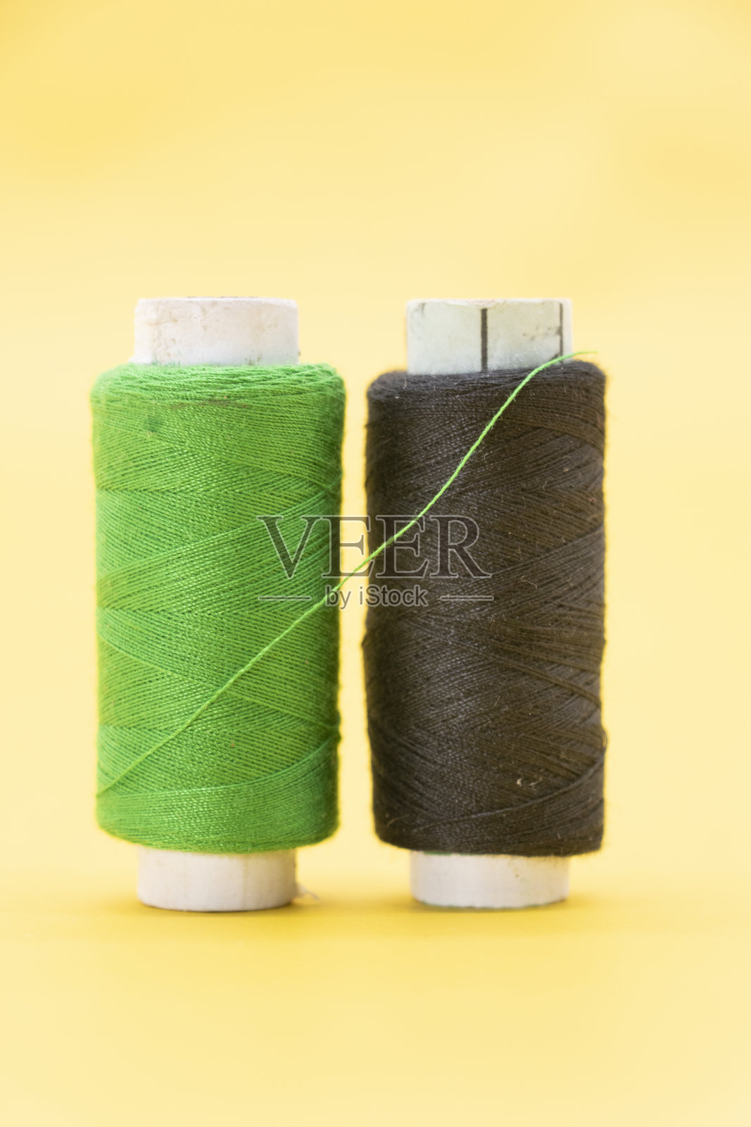 绿色和黑色的纱线或线轴在黄色的背景上照片摄影图片