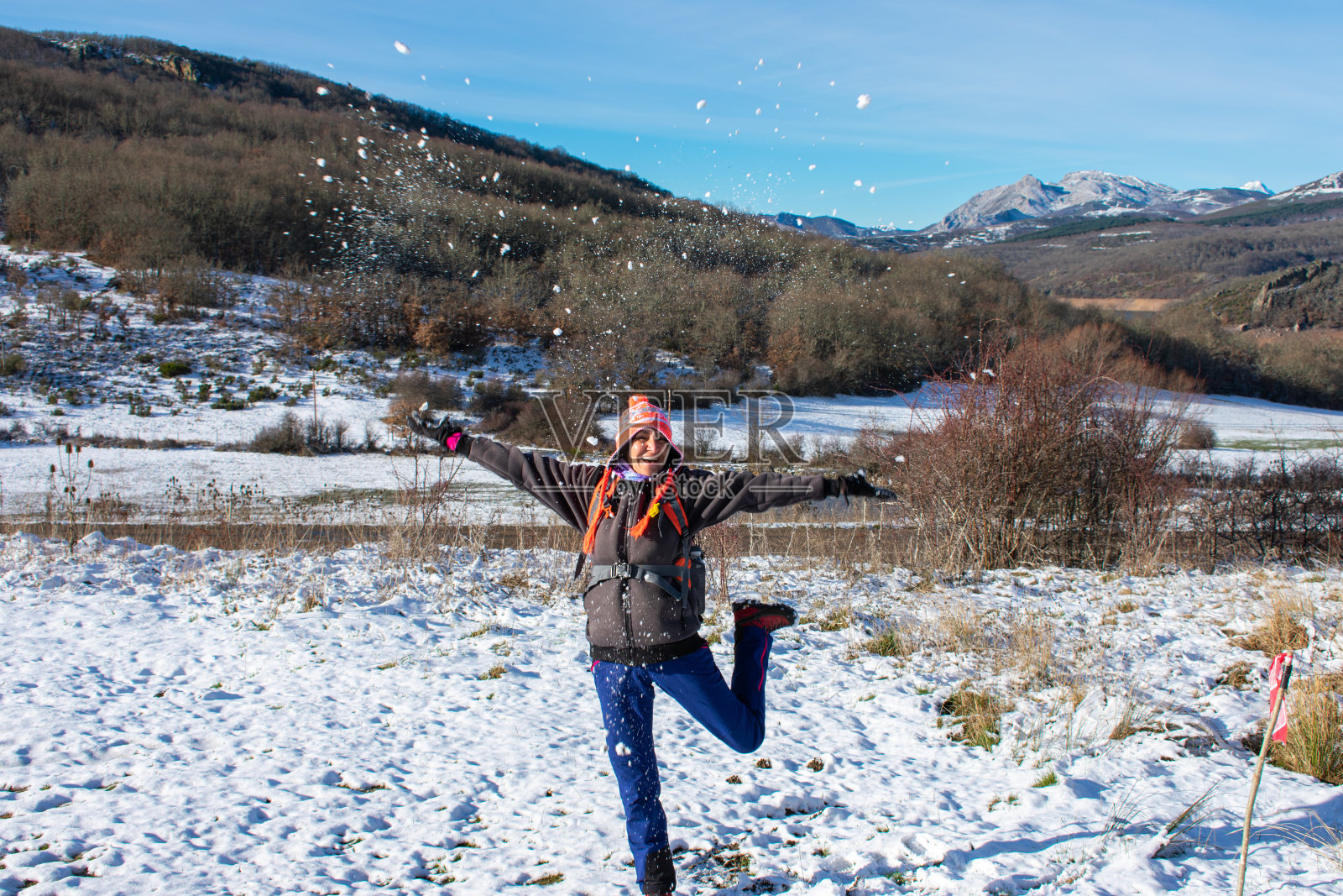 快乐的女人把雪扔到山上照片摄影图片
