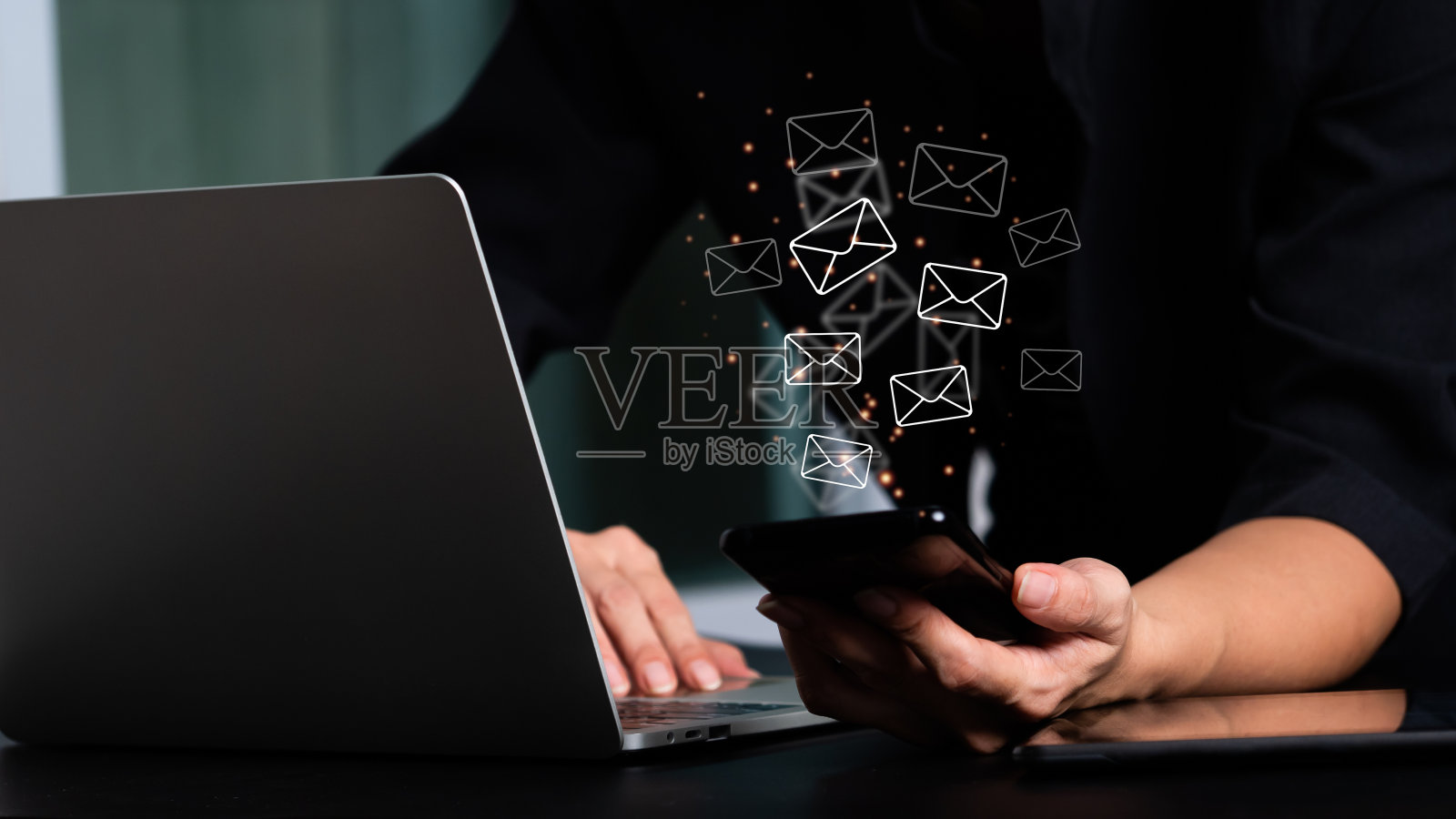 女人的手拿着手机和有电子邮件图标的笔记本电脑。电子邮件和联系我们的概念照片摄影图片