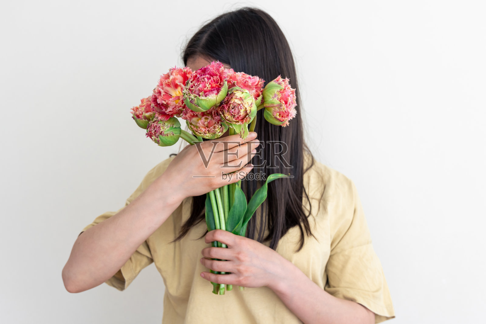 一个年轻的女人拿着一束白色背景的花。照片摄影图片