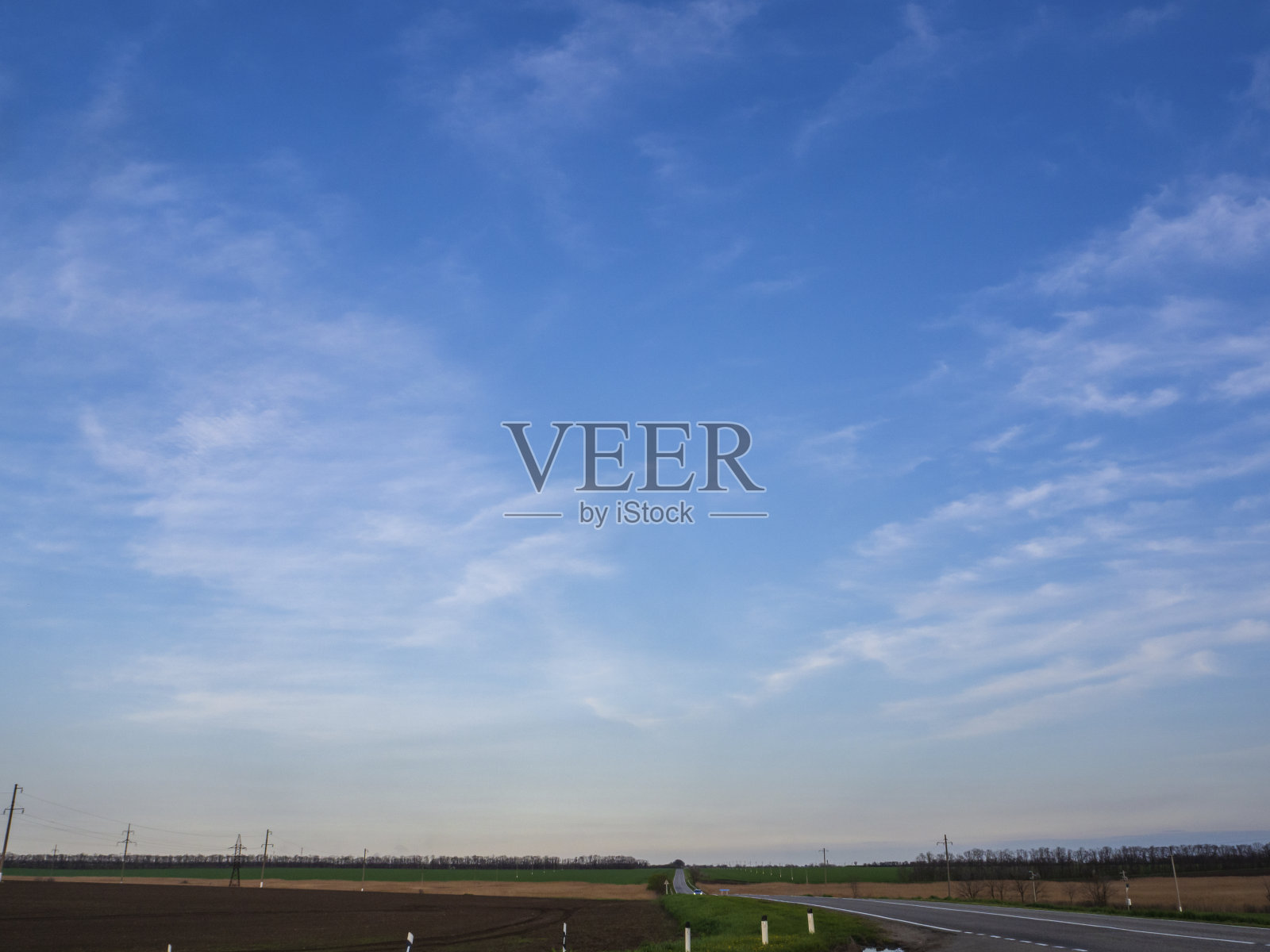 蓝天和柔软的云在柏油路上延伸到农业之间的距离。汽车旅行照片摄影图片