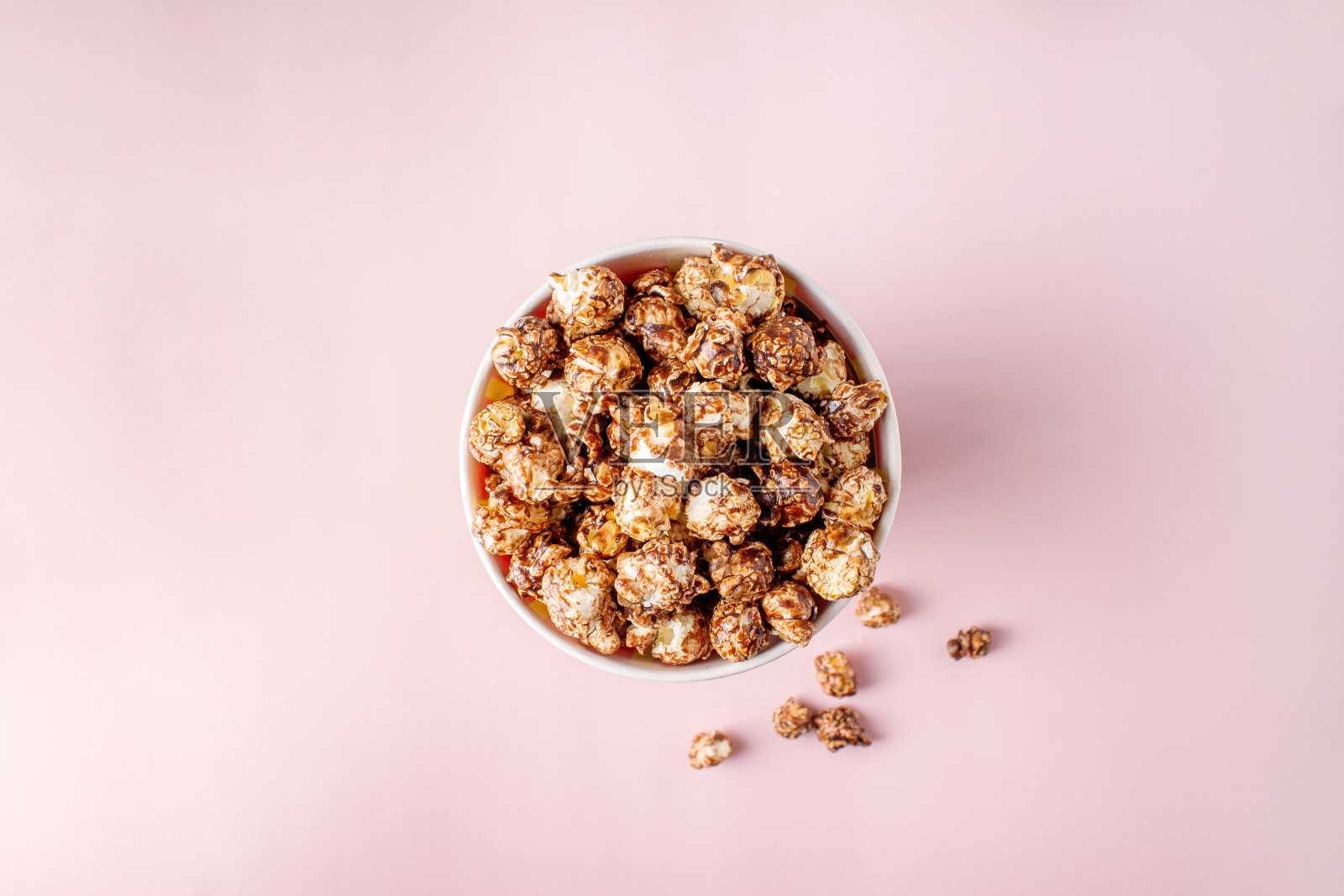 粉色背景下的纸桶里的巧克力爆米花，俯视图照片摄影图片