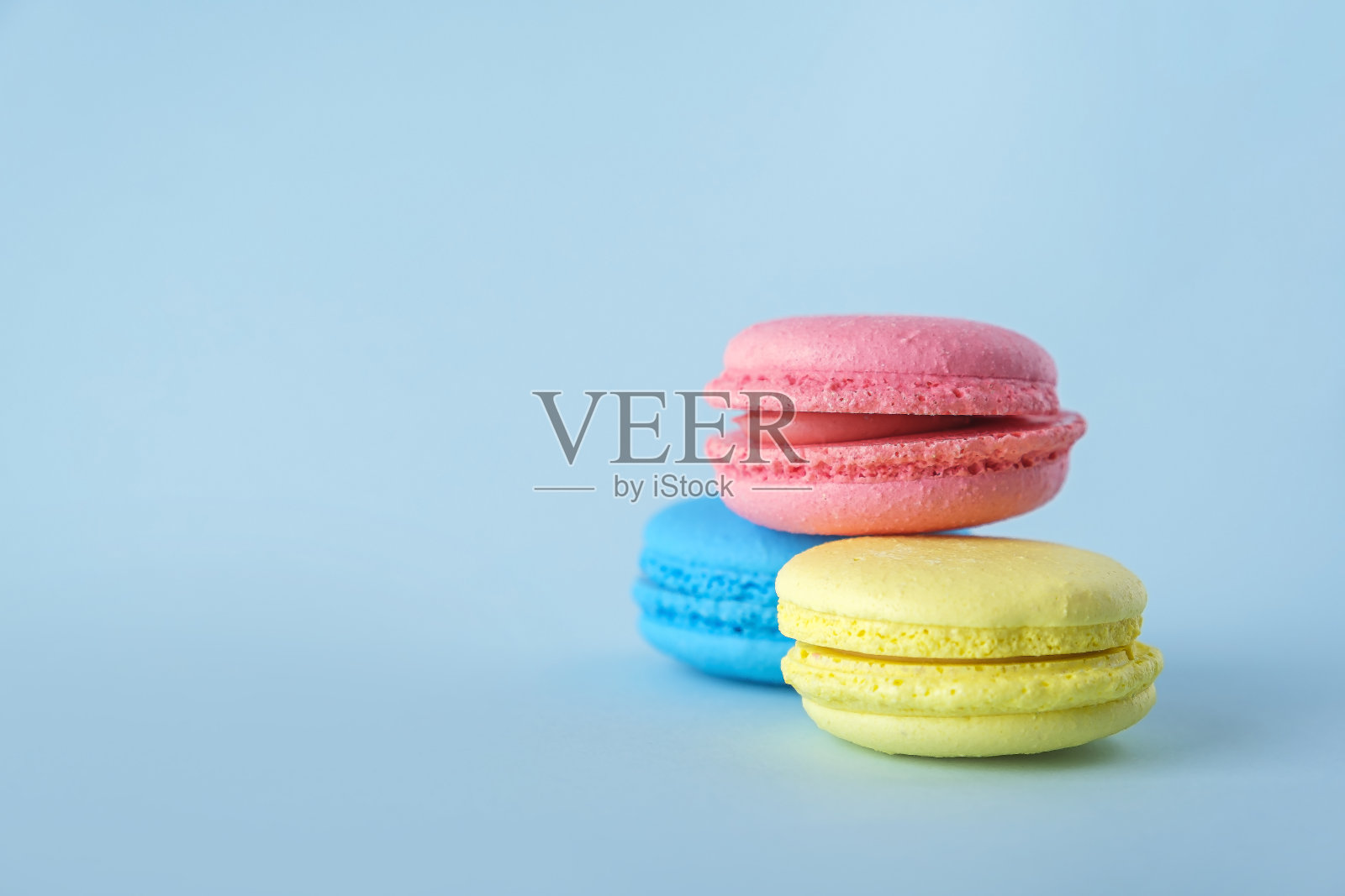 彩色的法式马卡龙饼干(马卡龙)在蓝色的背景。甜点，素食甜点照片摄影图片