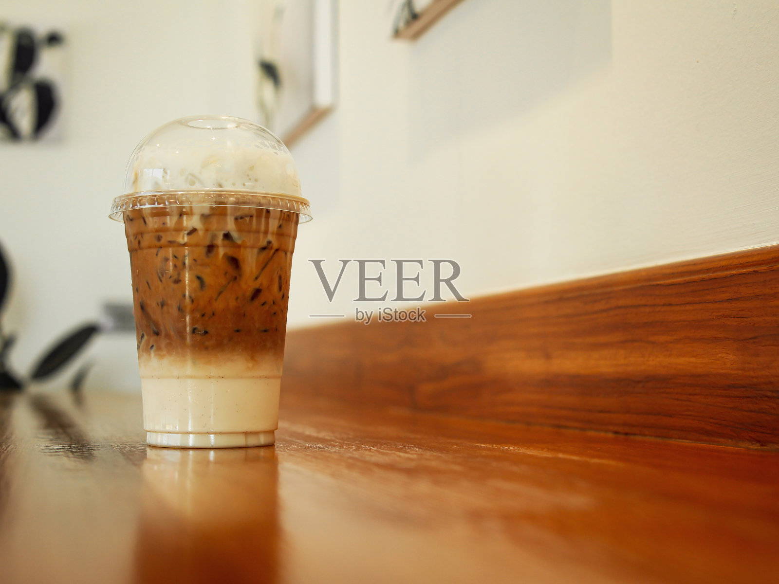 咖啡馆的木桌上放着塑料杯里的咖啡照片摄影图片