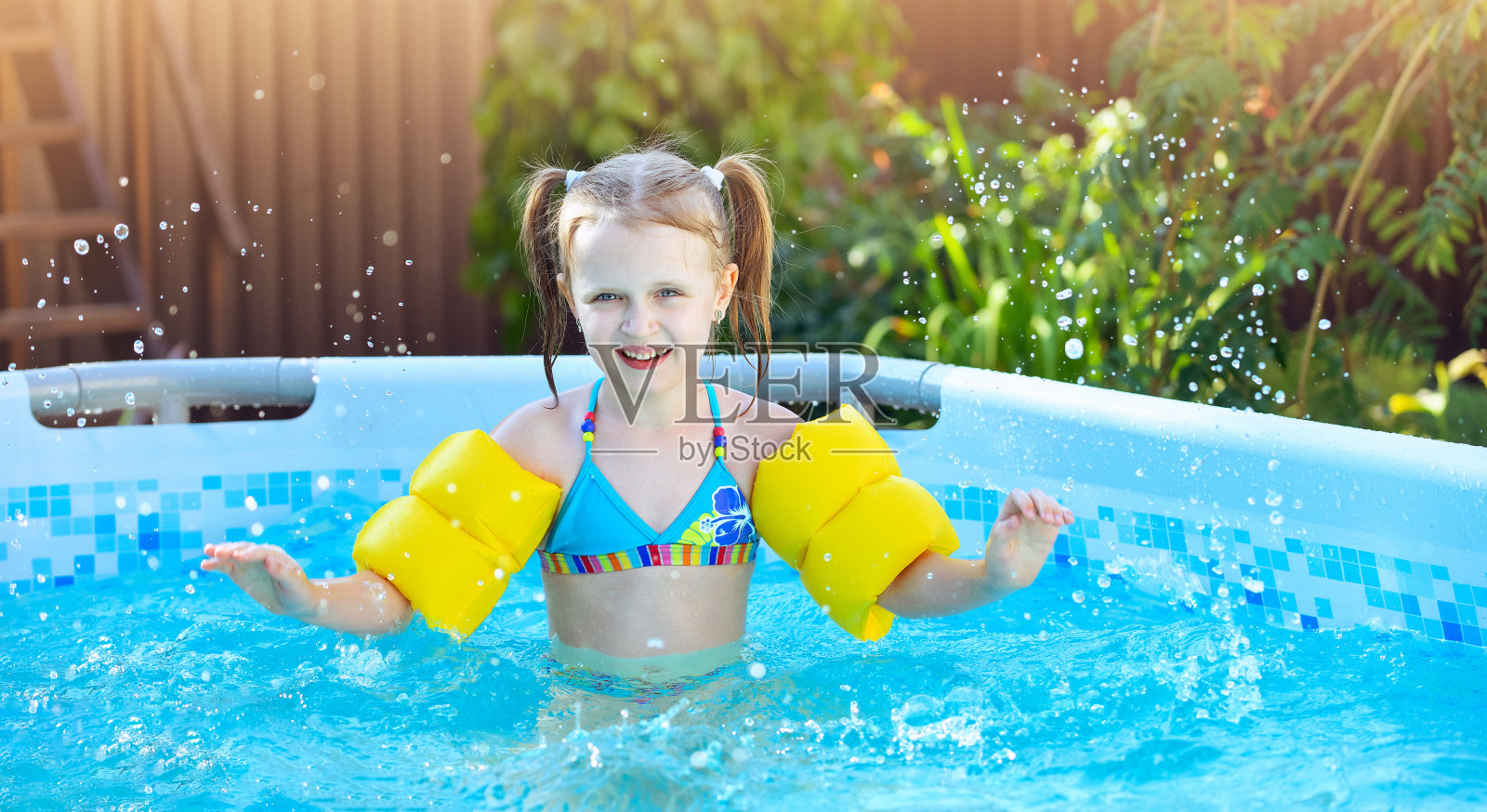 小女孩在自家花园的框架游泳池里戏水照片摄影图片