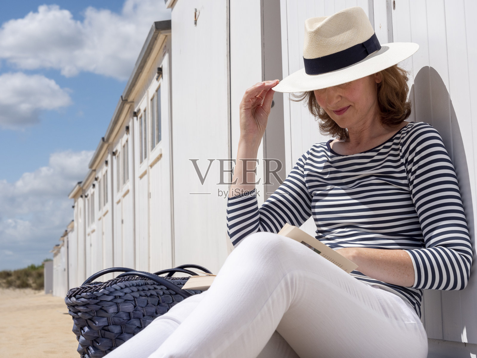 在比利时诺克基的海滩上看书的女人。照片摄影图片