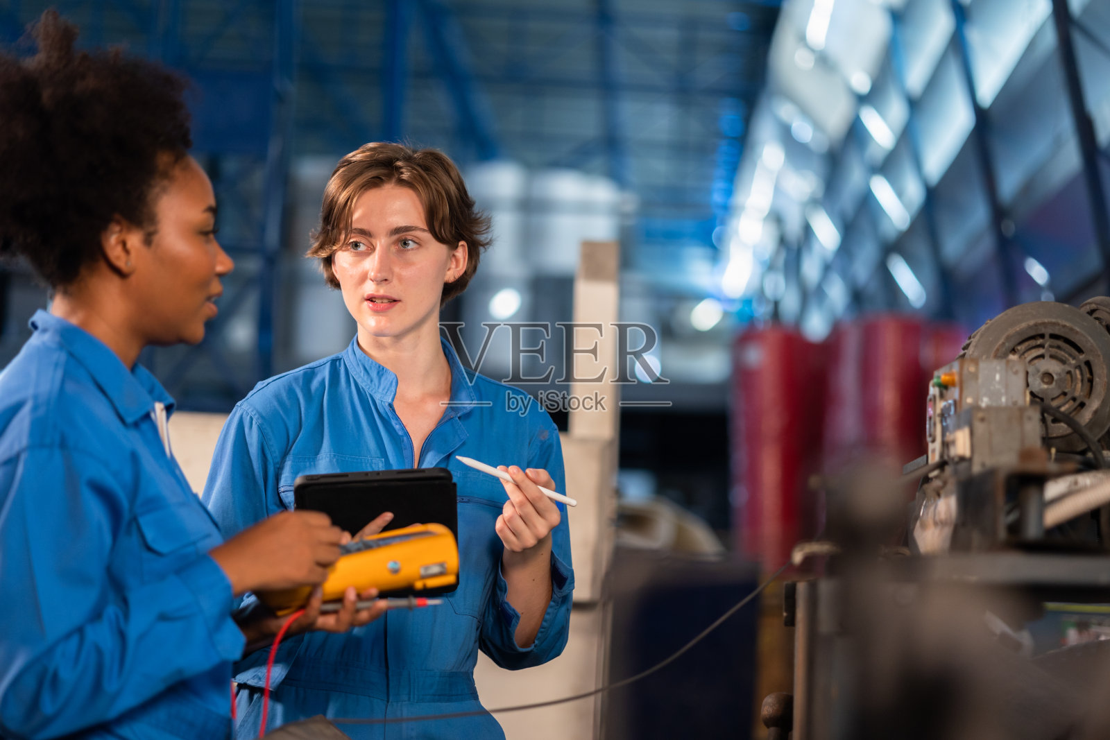 非裔美国人身穿防护服的年轻女工在工厂操作机器。在工业中工作的人。女工程师在工作场所的肖像。照片摄影图片