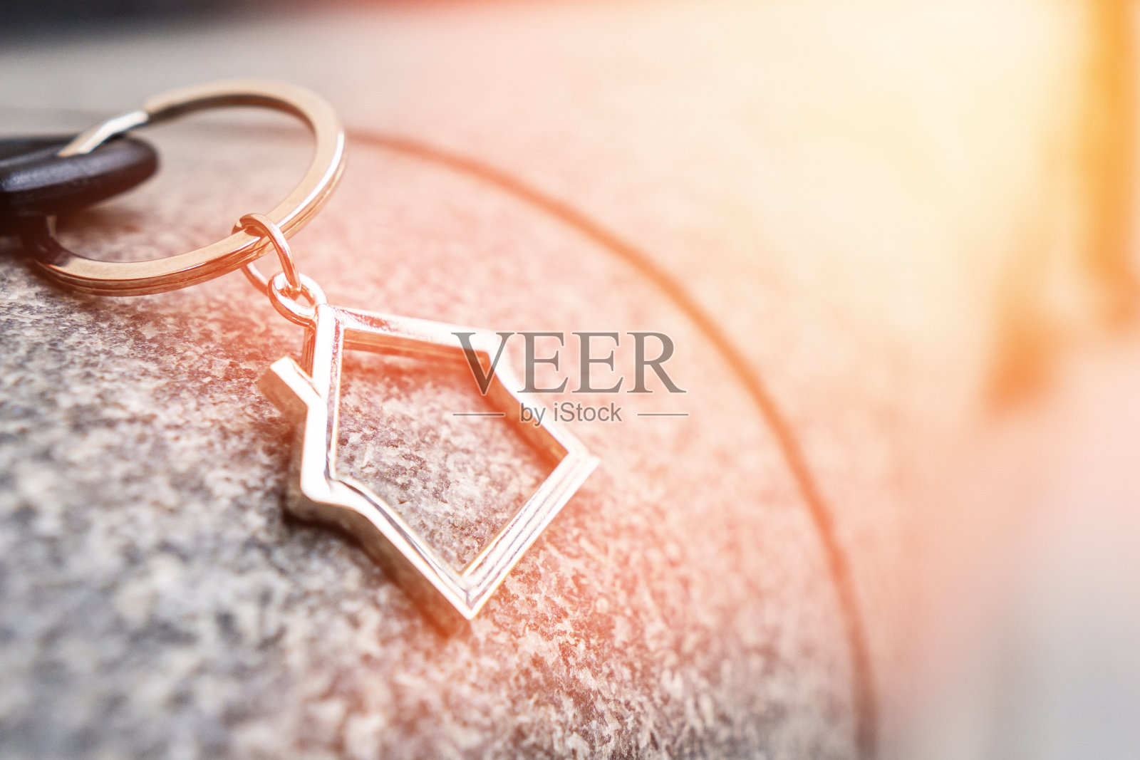 一个房子形状的钥匙链位于建筑的花岗岩立面上。照片摄影图片