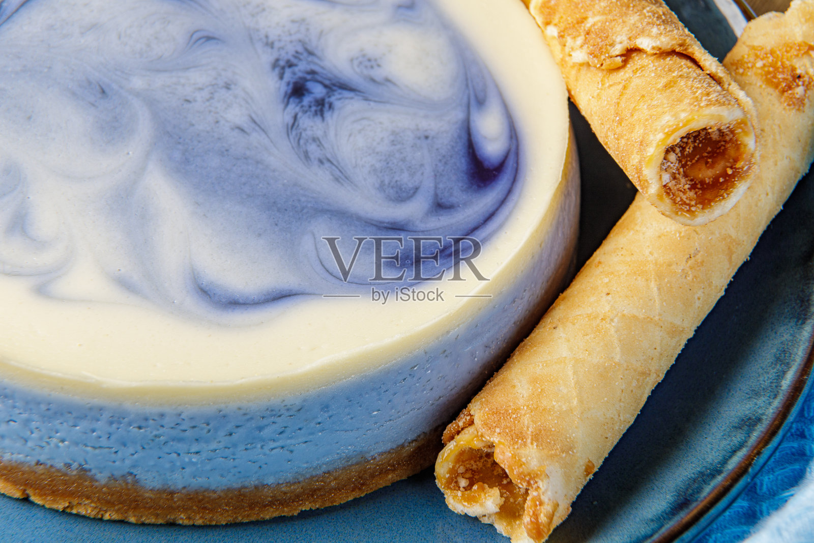 蓝盘子上放着奶酪蛋糕、蓝莓、糖果管和炼乳。特写镜头照片摄影图片