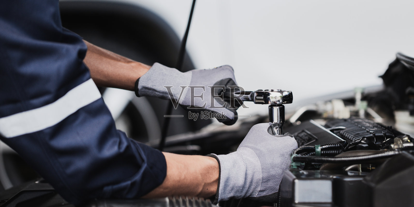 在车库里修理汽车发动机的专业技工。汽车修理服务。照片摄影图片