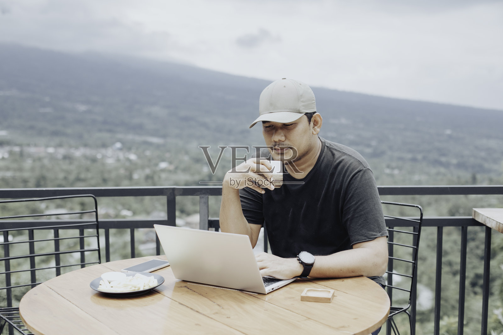 坐在咖啡店里用笔记本电脑的年轻人照片摄影图片