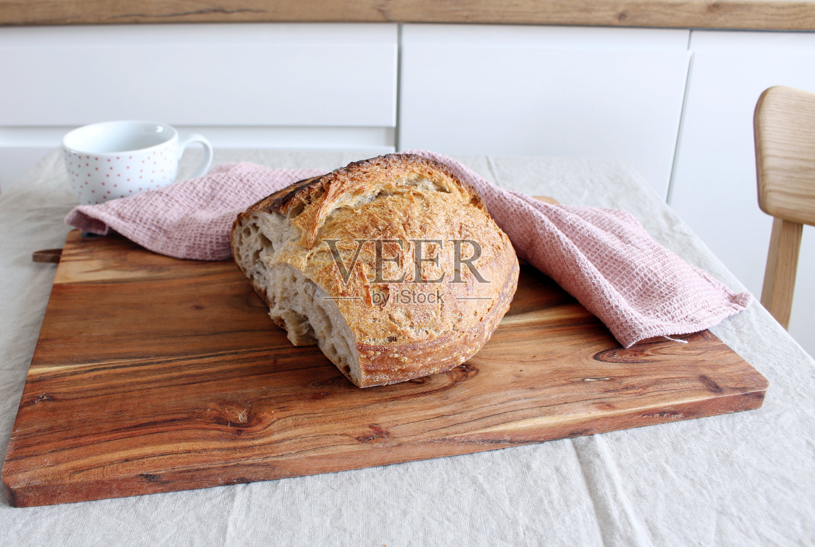 面包特写。厨房的桌子上放着新鲜出炉的金黄色面包皮的酸面包。照片摄影图片