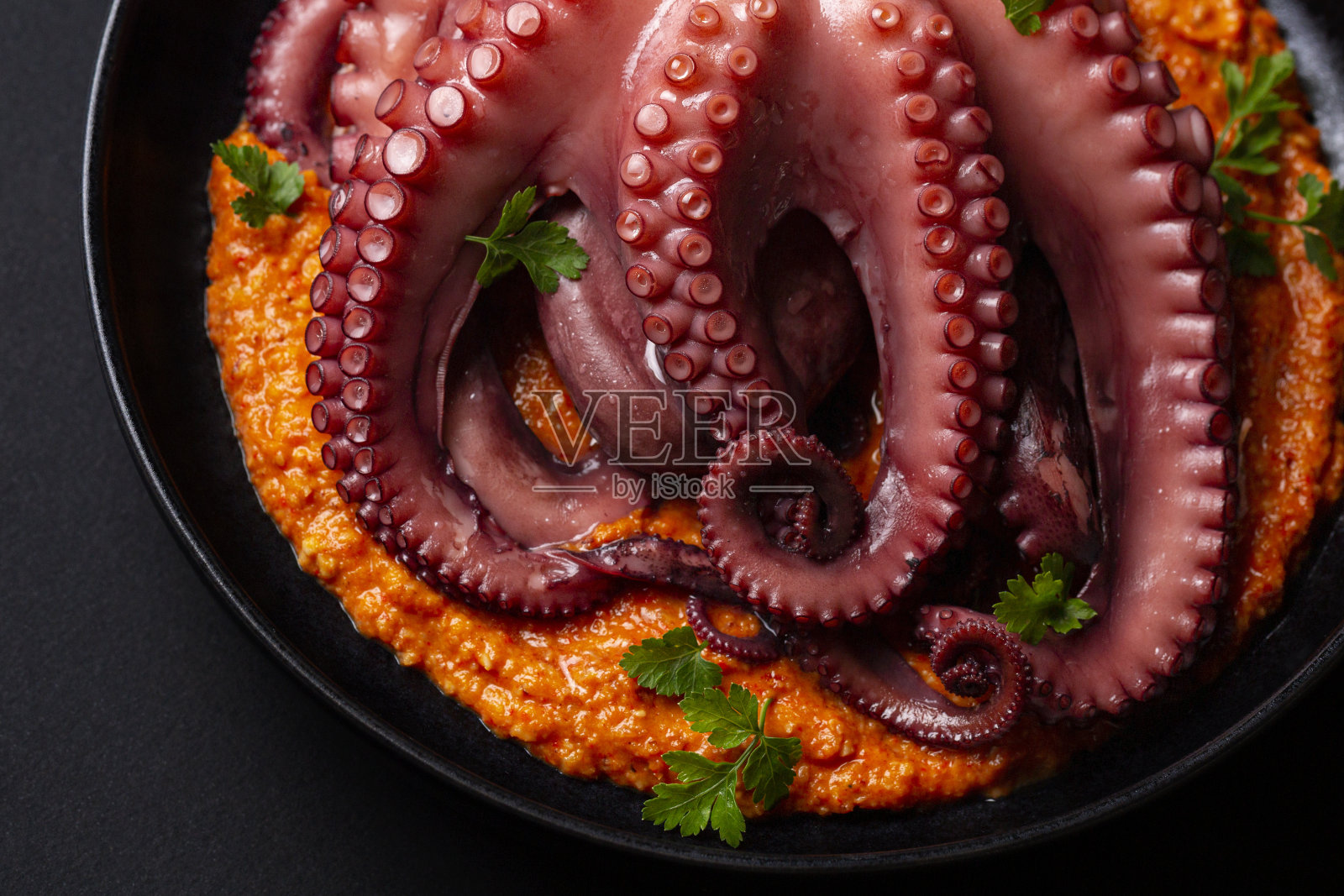 煮章鱼触须配罗梅斯科酱和欧芹。海鲜。关闭了。黑色背景。照片摄影图片