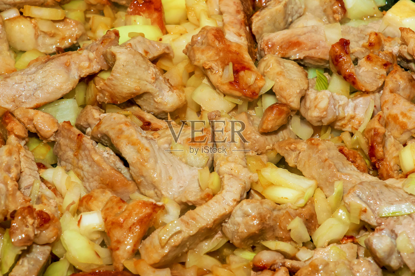 猪肉片和切碎的白洋葱，在热油锅里炸，近距离。照片摄影图片