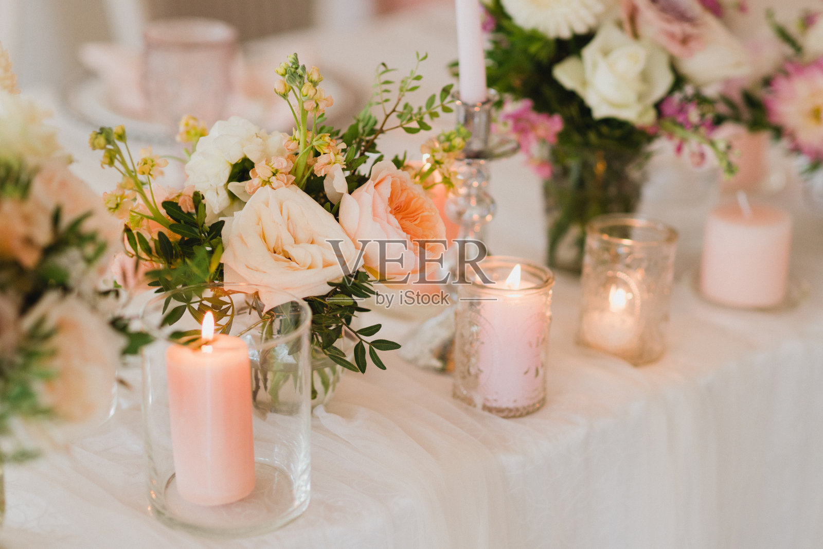 婚宴上的餐桌摆设。用美丽的花朵和绿色植物，蜡烛，摆放和盘子装饰的桌子。照片摄影图片