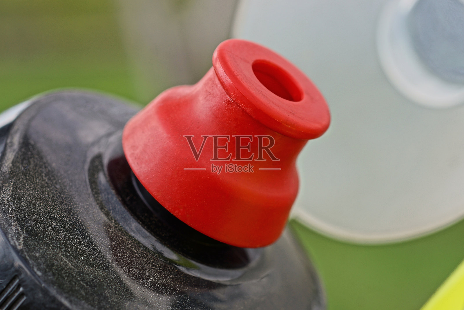 自行车上用红色盖子盖住的黑色塑料水瓶的一部分照片摄影图片