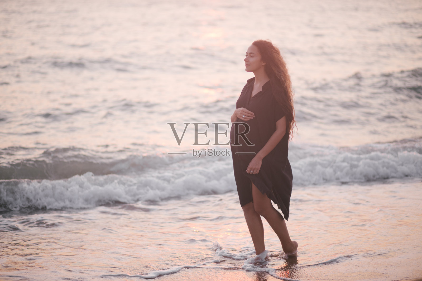 长头发的孕妇美女在沙滩上散步。照片摄影图片
