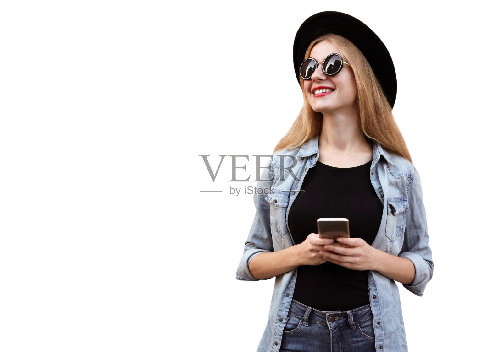 幸福微笑的年轻女子的肖像与智能手机看远处戴着黑色圆帽，牛仔裤夹克孤立在白色背景孤立，白色，背景照片摄影图片