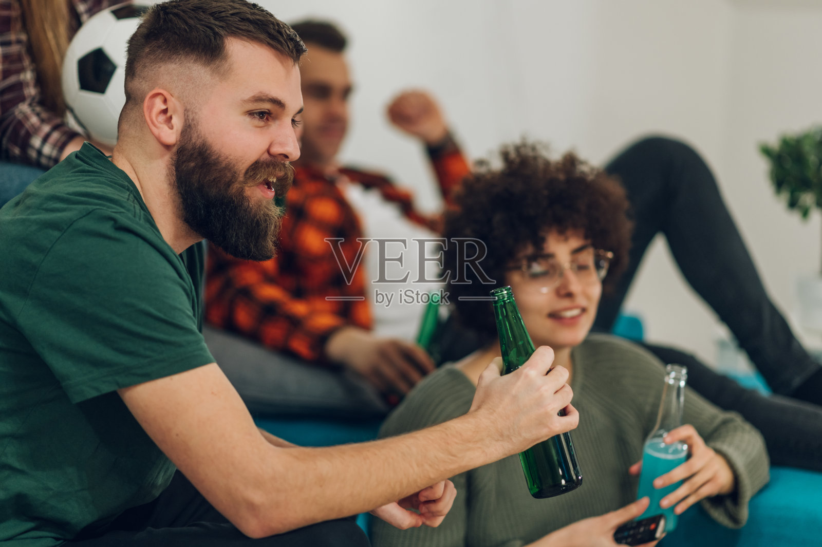朋友们在家里观看足球比赛并欢呼照片摄影图片