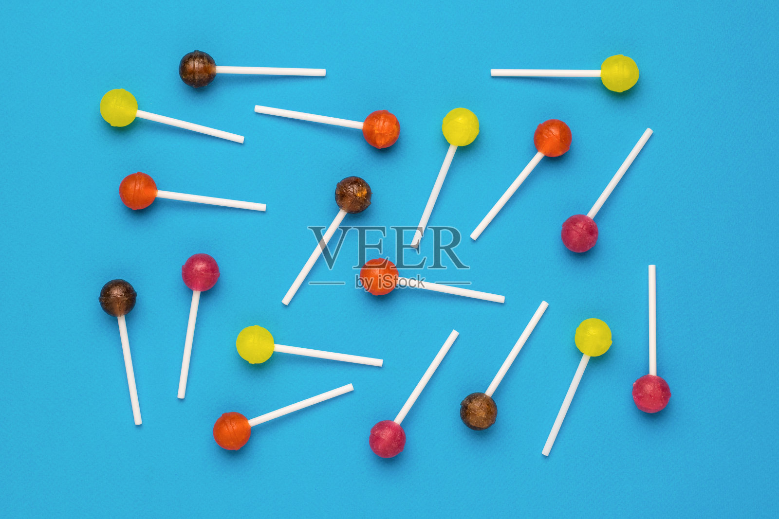 彩色的棒棒糖散落在蓝色的背景上。最小的概念。甜蜜的糖果。照片摄影图片