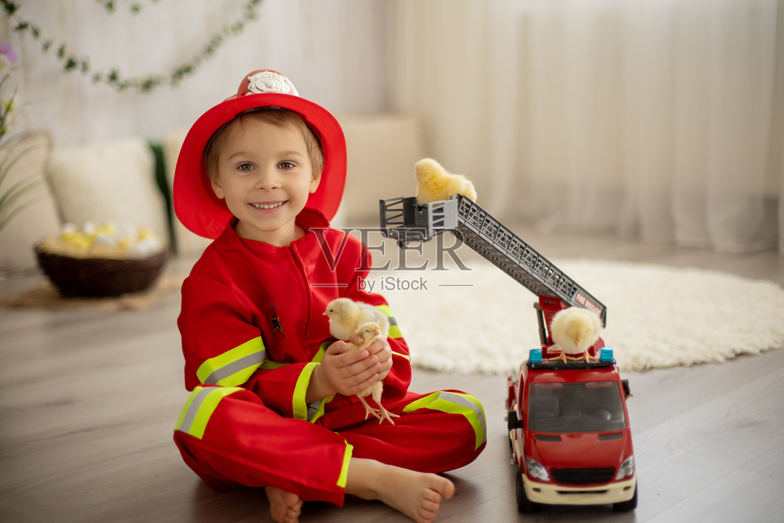 在家玩消防车玩具和小鸡的小男孩照片摄影图片
