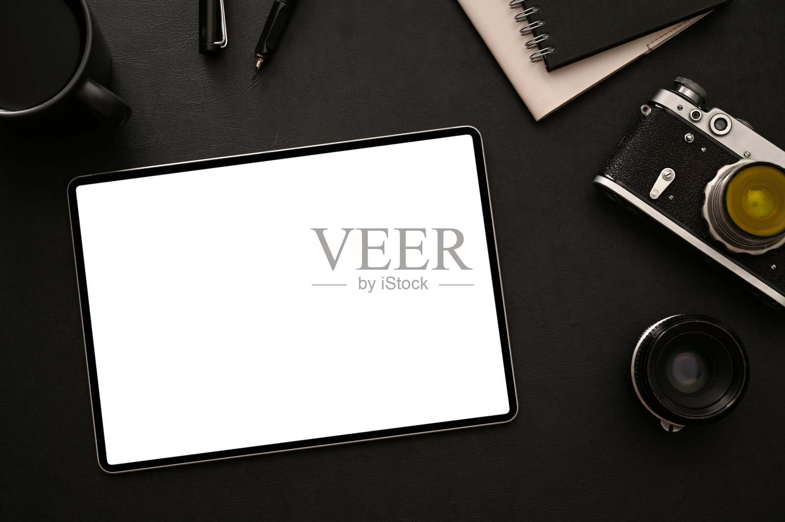 带有平板电脑、复古相机、镜头和配件的现代黑暗时尚摄影师工作区照片摄影图片