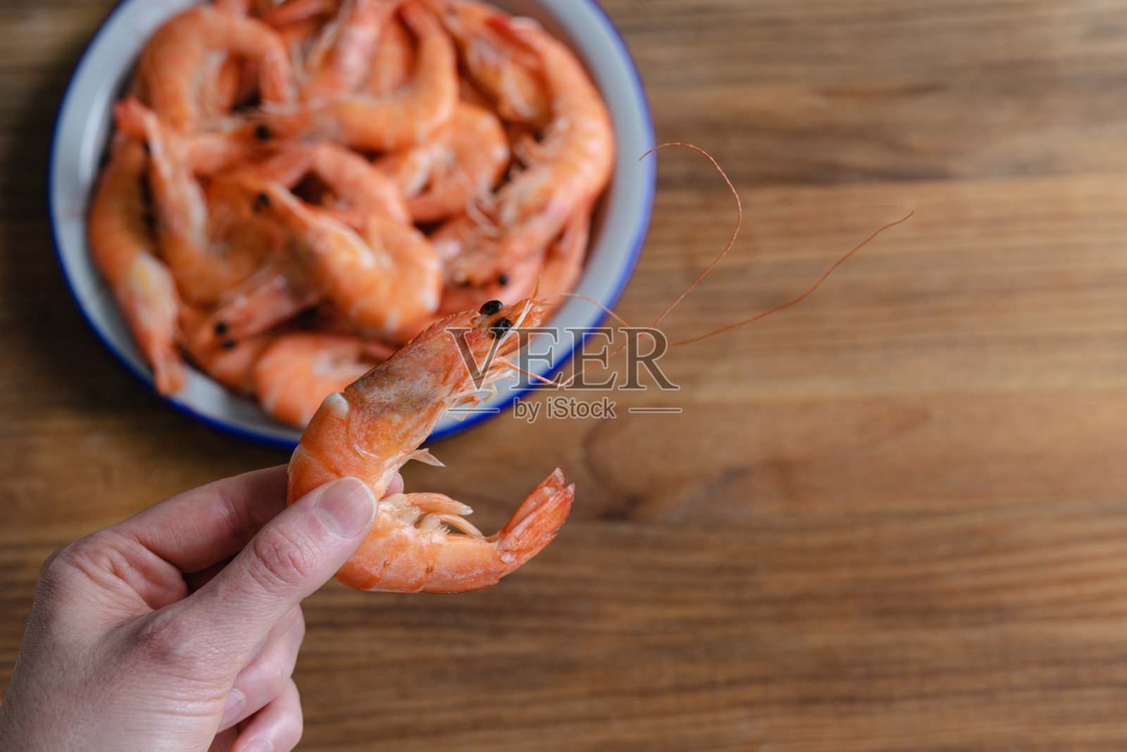 手拿着一个虾与全盘的木制背景。副本的空间。照片摄影图片