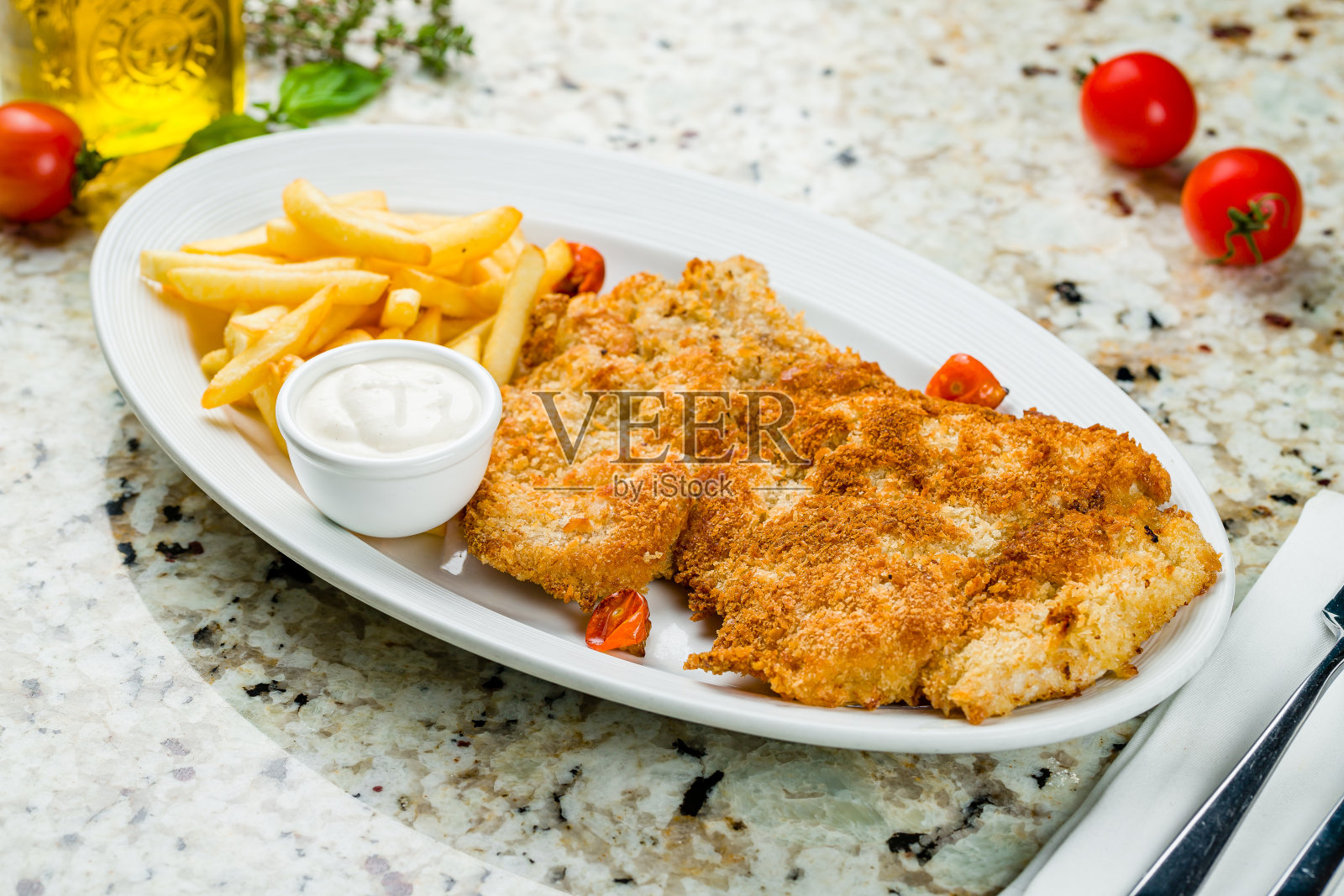 米兰的鸡肉配上薯条和酱汁，白色的盘子放在大理石桌子上照片摄影图片