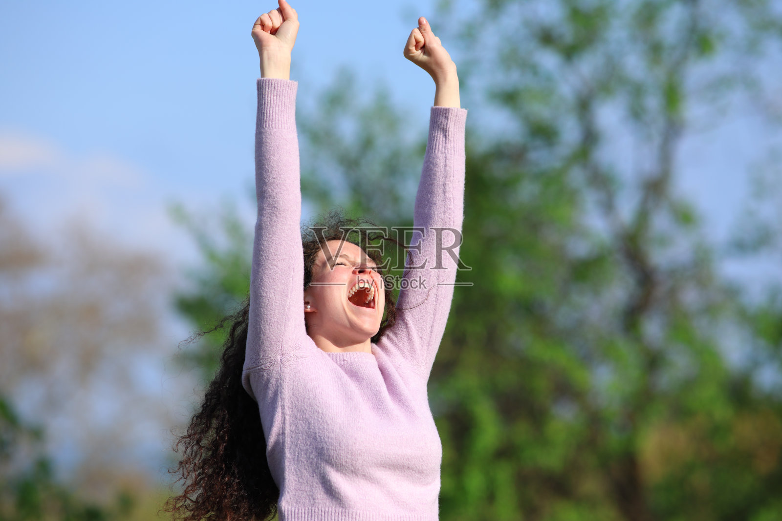 兴奋的女人在公园里举起手臂庆祝美好的一天照片摄影图片
