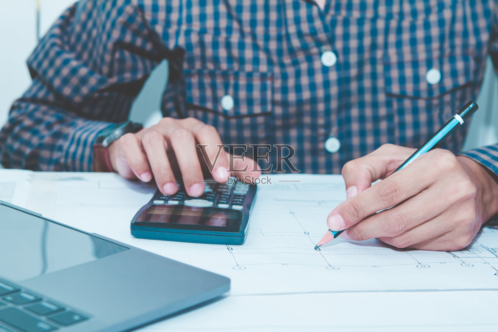 工程师使用计算器计算结构和强度建筑设计写作工作蓝图与笔记本电脑的办公桌在办公室。概念建筑师在家工作照片摄影图片