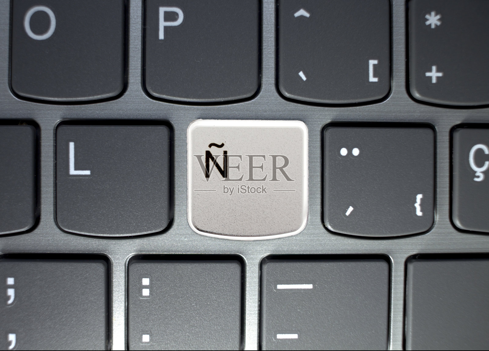 灰色色调的笔记本电脑键盘，西班牙语键盘的字母n突出显示照片摄影图片