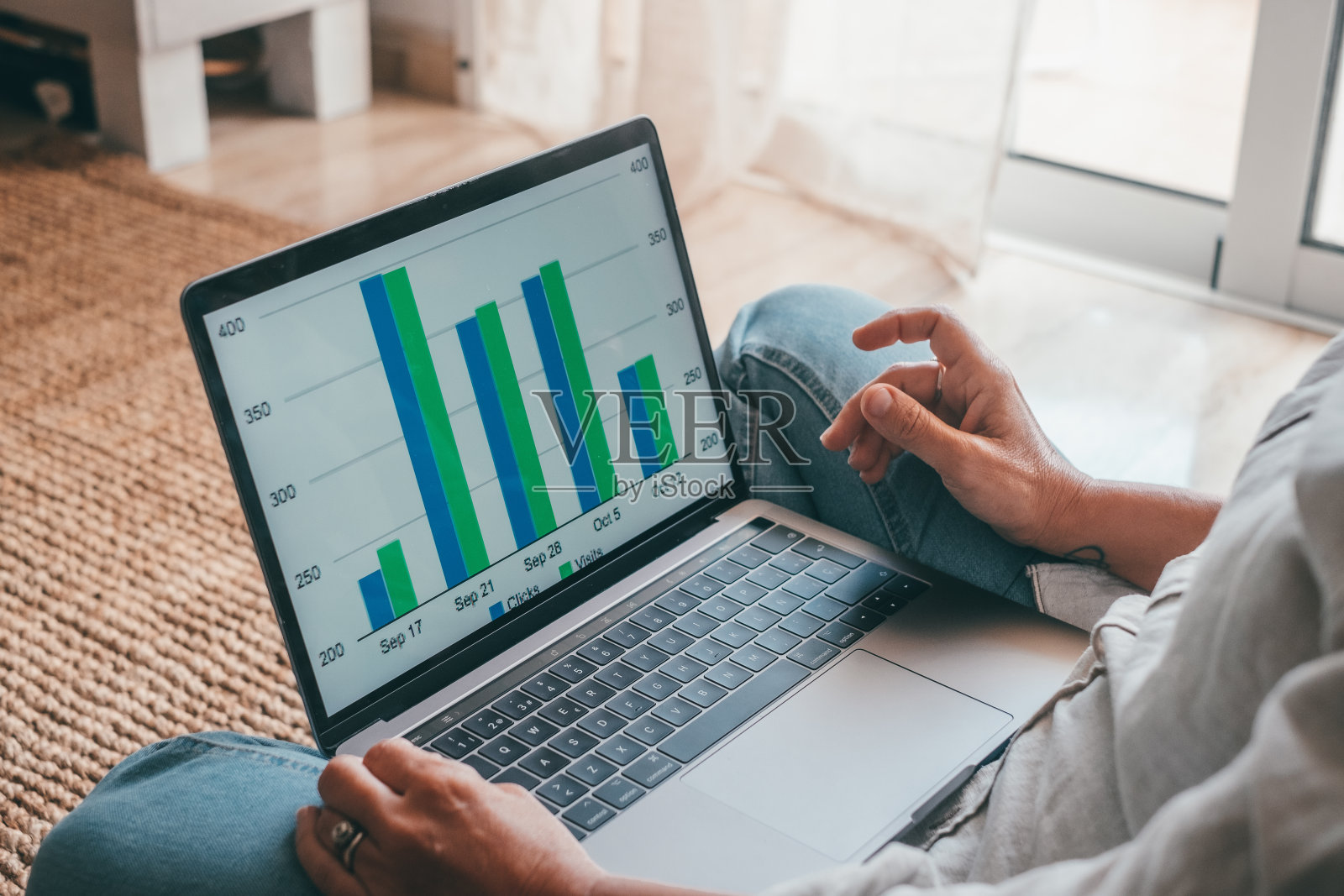 近后方的年轻女子使用笔记本电脑和计算器，在项目上工作，检查财务文件，坐在家里的桌子，看着电脑屏幕与图表，计算账单照片摄影图片