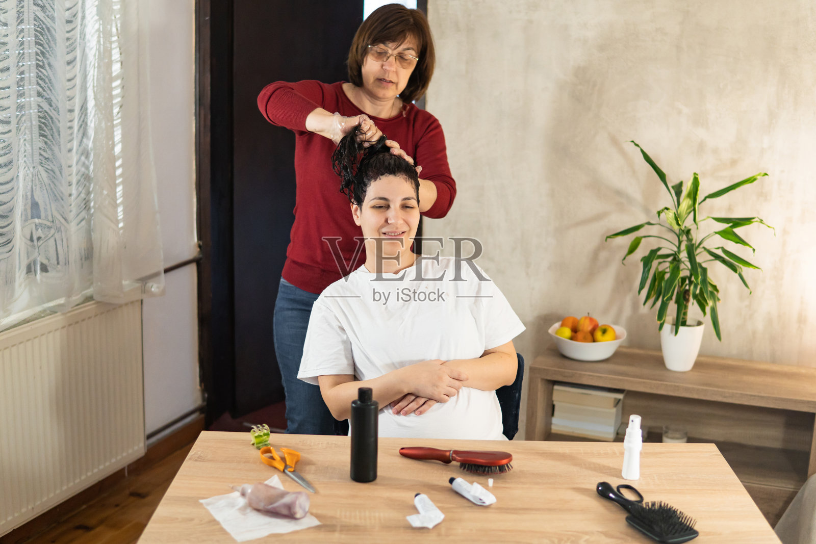 一位老年妇女在家给怀孕的女儿染头发。照片摄影图片